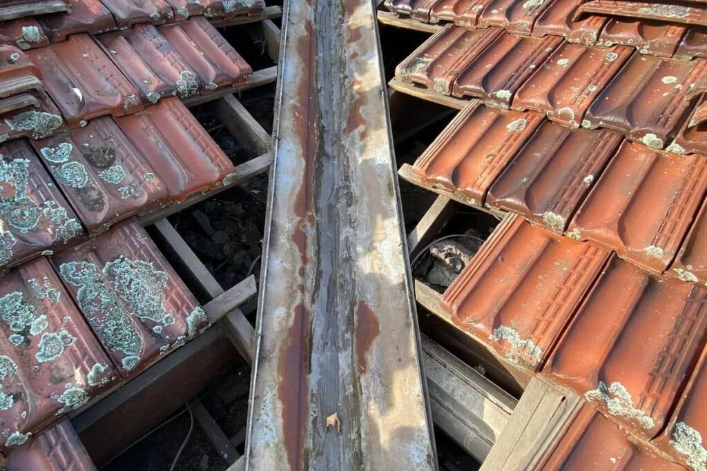 Rusted valley iron running between terracotta roof tiles